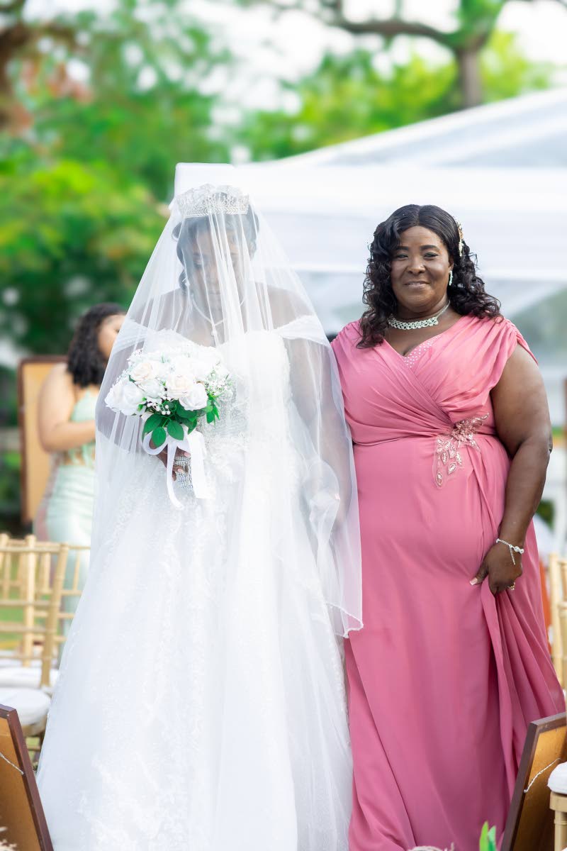 Bride Dawna-Kay Williams-Hylton makes her way down the aisle with her mother, Carmen Roberts-Wright, who stepped into the role in her late father’s absence.