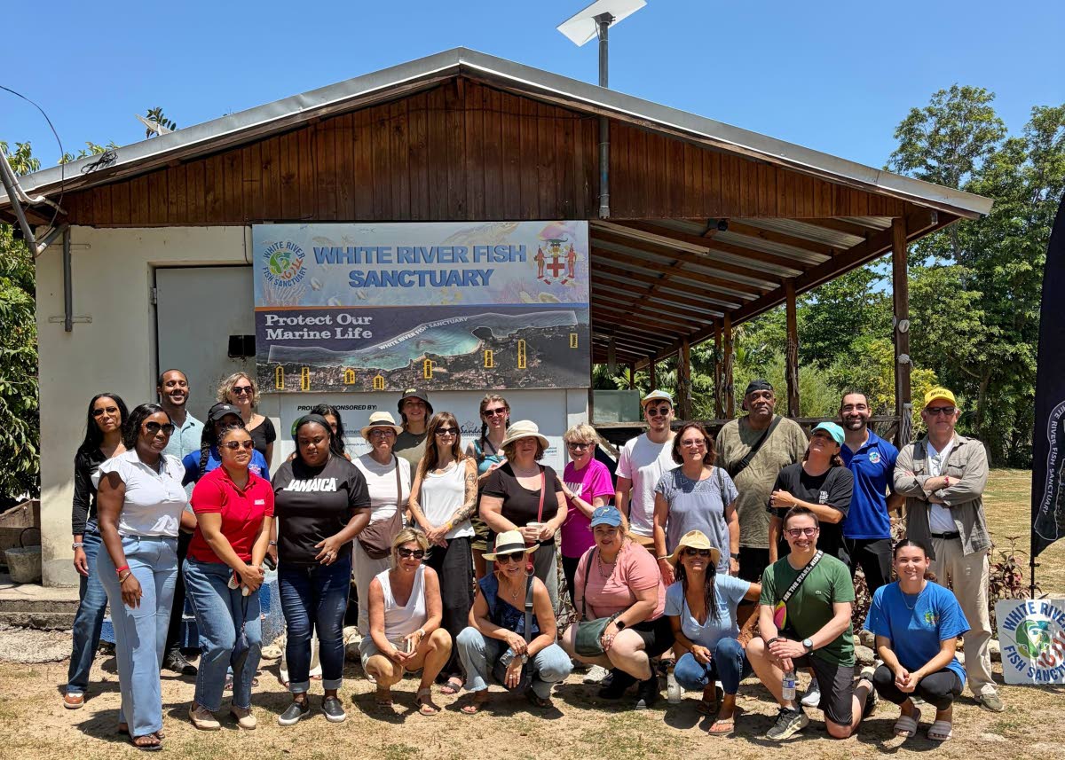 White River Fish Sanctuary Manager Jonathan Hernould (second right, standing) and Francesca Russell, coral restoration officer (right, crouching), pose with a group of JAPEX 2026 visitors during their tour of the sanctuary.