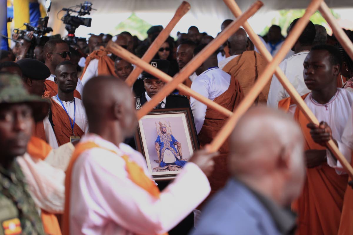 A Ugandan security officer carries a portrait of Tooro’s King Oyo Nyimba during his funeral procession in Fort Portal, Uganda. 