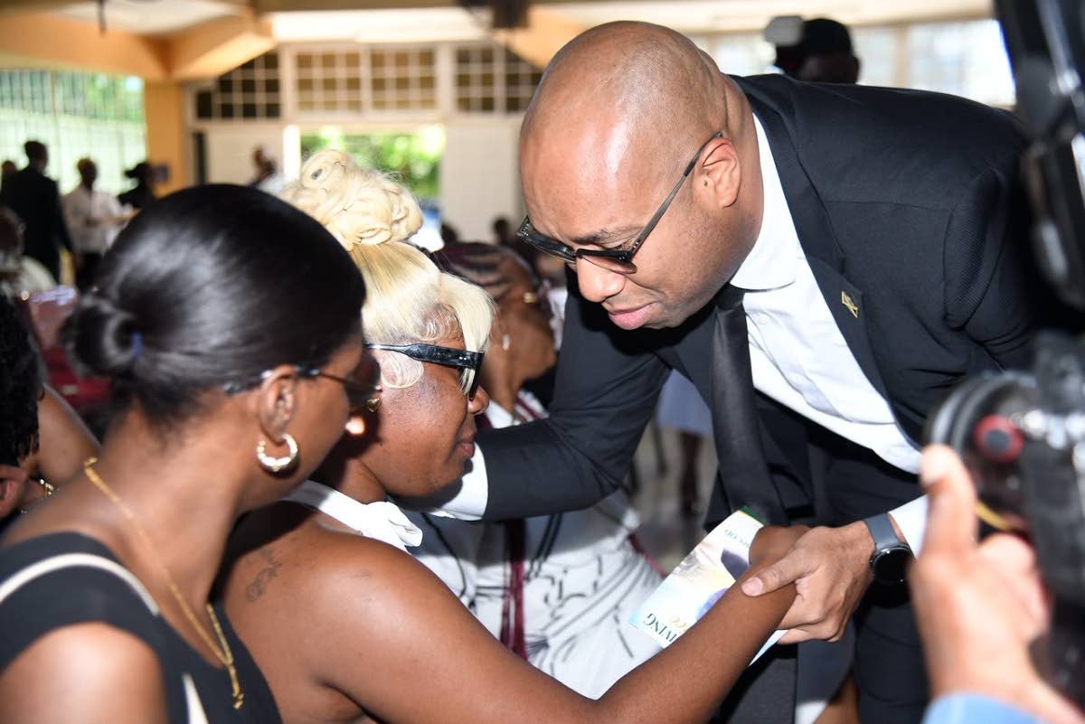 State Minister in the Ministry of Industry, Investment and Commerce Delano Franklin consoles Shai-Ann Henry, daughter of late veteran journalist Balford Henry, before the start of the funeral service on Saturday.