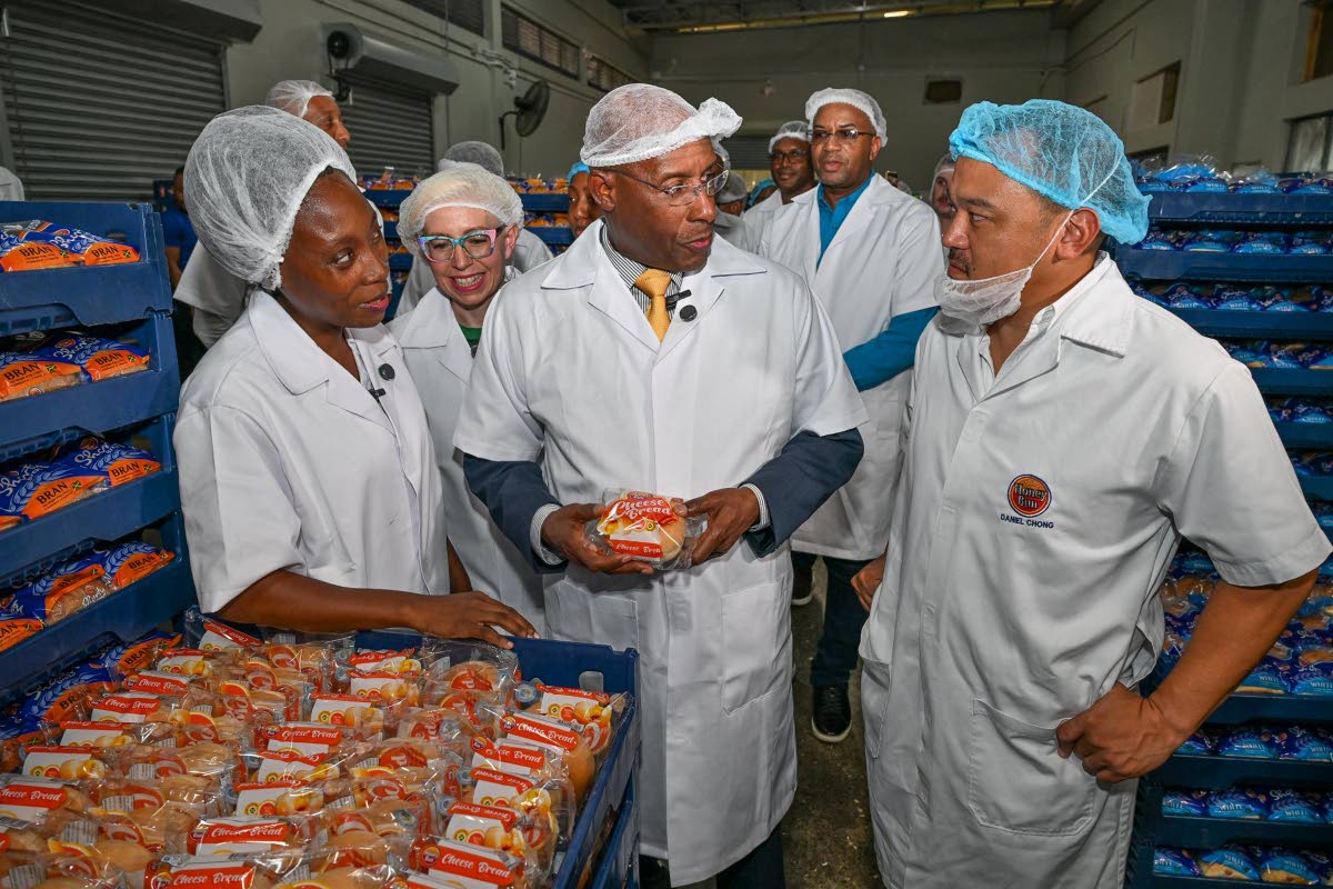 Minister of Industry, Investment and Commerce, Senator Aubyn Hill (centre), converses with Honey Bun Chief Executive Officer, Daniel Chong (right), during a tour of the company’s new manufacturing facility at the MJS Industrial and Technology Park in Spa