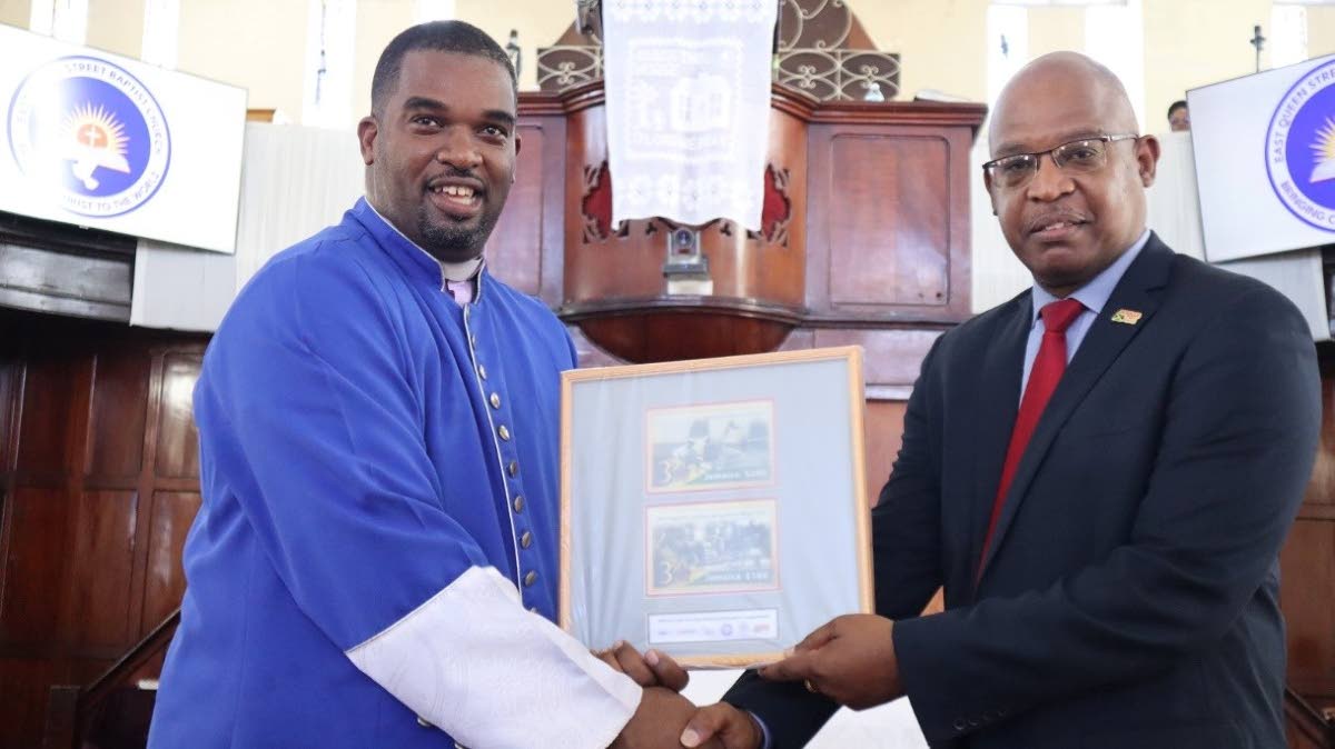 Rev Dr Devere Nugent, Pastor of East Queen Street Baptist Church, is presented with a framed display of stamps depicting modes of transportation from the 1930s by Lincoln Allen, Postmaster-General/CEO of Jamaica Post.