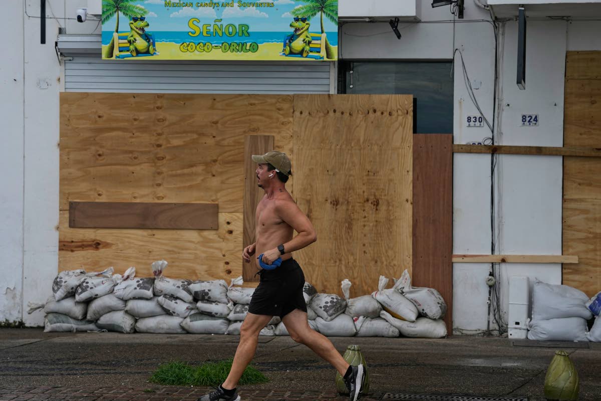 Un corredor pasa junto a una tienda tapiada tras el paso del huracán Simón en Puerto Vallarta (México), el lunes 12 de octubre de 2026. (Foto AP/Fernando Llano)