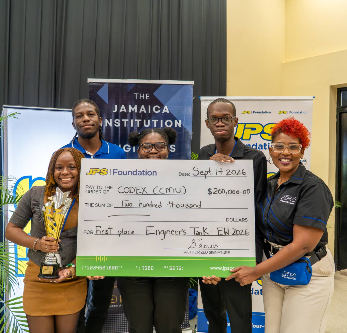 JPS Foundation Head, Sophia Lewis (right) presented the symbolic winning cheque  of $200,000 to the first-place team from Caribbean Maritime University (CMU) which won the inaugural Jamaica Institution of Engineers’ Engineer’sTank pitch competition 