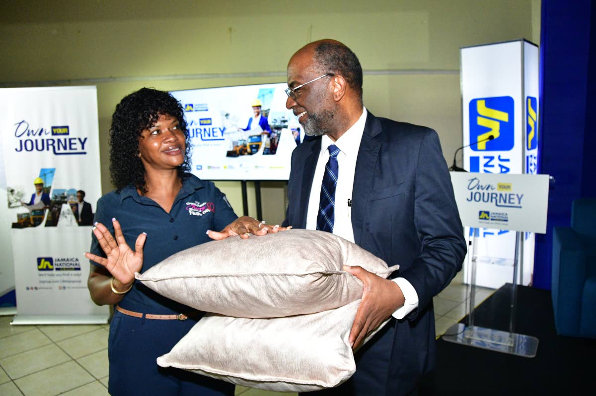 Denise Wheatle (left), operator of Creative Little Kerry House of Fashion and a client of JN Bank Small Business Loans, gifted Earl Jarrett, chief executive officer, The JN Group, a pair of cushions she made. The occasion was a JN members meeting held at t