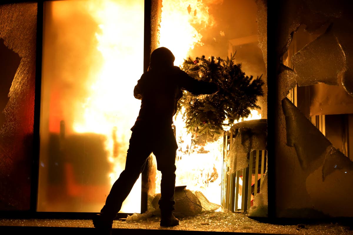 A hooded protester vandalises the Justice Ministry during clashes in Tirana, Albania, October 14, 2026, as students joined the Flamingo anti-government movement.