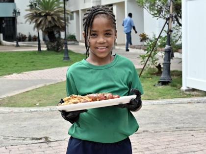 Chef Jonathan Simpson’s daughter, Jay-Ann Simpson, smiles for the camera as she presents one of her father’s signature dishes: the seafood boil.