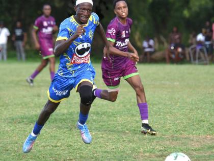 Cedric Titus High’s Terron Eccleston (left) dribbles away from William Knibb Memorial High’s Jaheem Brown (right) during their Zone D match in the ISSA daCosta Cup at William Knibb’s playing field yesterday. Ecclestion scored twice in his team’s 2-