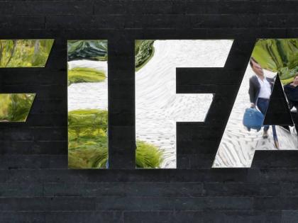 In this May 27, 2015 file photo two persons are reflected in the FIFA logo at the FIFA headquarters in Zurich, Switzerland.