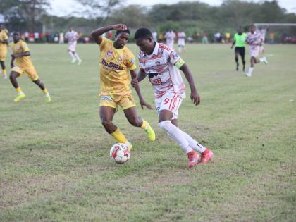 Glenmuir’s Orane Watson goes on a dribble while being chased by Garvey Maceo’s Ajani Johnson during their ISSA daCosta Cup football match at the Garvey Maceo playfield yesterday.
