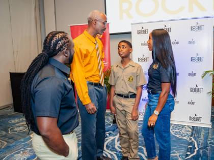 Dr Jermaine McCalpin (left), executive director of the Pocket Rocket Foundation, and Shelly-Ann Fraser-Pryce, founder of the foundation, listen attentively as Cary Fletcher (second left) shares the accomplishments of his son, Michael Fletcher.