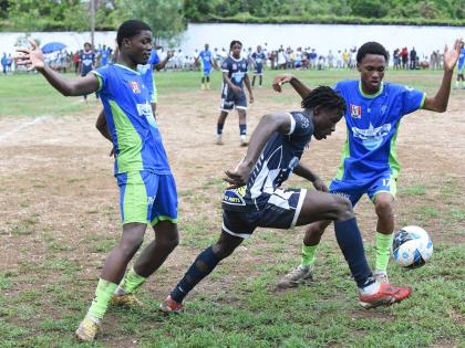  Jamaica College’s Duwayne Burgher (centre) attempts to dribble  past Serani Brown (left) and Antoinne Burton of  Vauxhall High during their Manning Cup football match at Vauxhall yesterday. The game ended in a 1-1 draw.