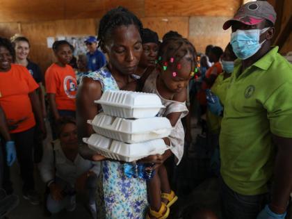 A woman carrying a child walks away with food from the World Food Program (WFP) at the Jean Marie Vincent High School which has been turned into a shelter for families displaced by gang violence in the Tabarre neighbourhood of Port-au-Prince, Haiti.