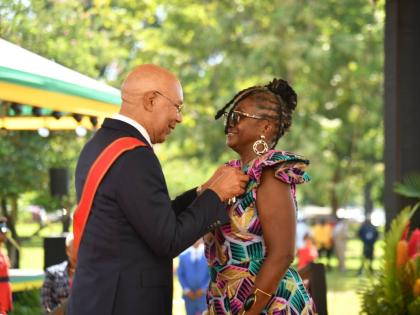 Dr Michelle Holt (right) is all smiles as she receives the Order of Distinction from Governor General Sir Patrick Allen during the Ceremony of Investiture and Presentation of National Honours and Awards on the lawns of King’s House yesterday.