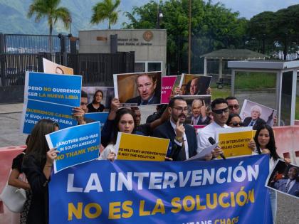 Gabriel Cabrera, president of the Venezuelan Youth Center for Democracy, gives a statement outside of the United States embassy with members of the organisation holding signs that read in Spanish “Intervention is not the solution”, in reference to US w