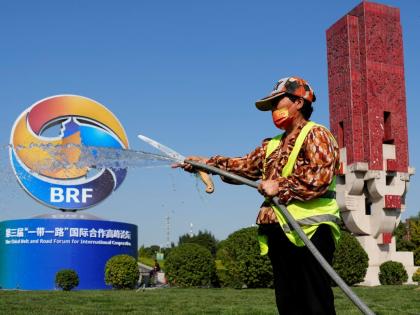 A gardener waters the grass near the logo for the Belt and Road Forum in Beijing, Monday, October 16, 2023. China’s Belt and Road Initiative looks to become smaller and greener after a decade of big projects that boosted trade but left big debts and rais