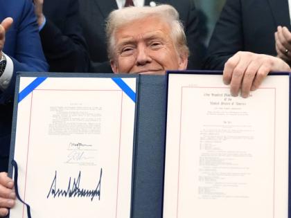 President Donald Trump displays the signed the funding bill to reopen the government, in the Oval Office of the White House, Wednesday, November 12, 2025, in Washington. (AP Photo/Jacquelyn Martin)
