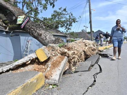 A man walks past a business place in St Ann which was damaged by an uprooted tree during Hurricane Melissa.