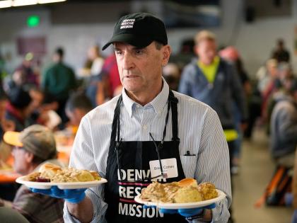 Volunteer Brent Cohen carries plates of food to guests during the annual Thanksgiving banquet at the Denver Rescue Mission on November 22, 2023, in Denver, Colorado.