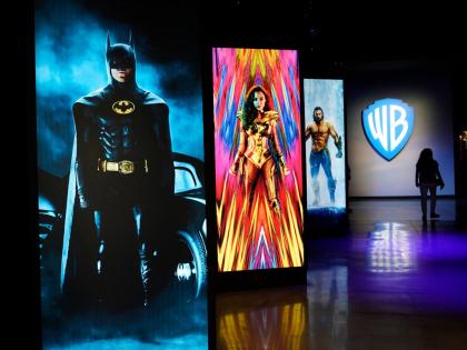 In this June 24, 2021, photo, a visitor walks past portraits of DC Comics superheroes as she enters the ‘Action and Magic Made Here’ interactive experience at the Warner Bros Studio Tour Hollywood media preview in Burbank, California.