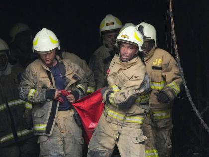 Rescuers carry out the body of a victim from the site of a fire in Jakarta, Indonesia on December 9, 2025. 