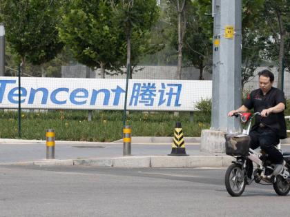 
In this August 7, 2020 photo, a man rides past Tencent headquarters in Beijing, China, on August 7, 2020.