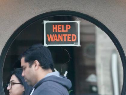 Pedestrians walk past a ‘Help Wanted’ sign posted on the door of a restaurant in San Francisco in April 2023. 
