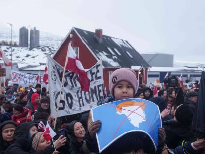 A boy holds a crossed-out map of Greenland topped by a hairpiece symbolising US President Donald Trump, during a protest against Trump’s policy towards Greenland in front of the US Consulate in Nuuk, Greenland