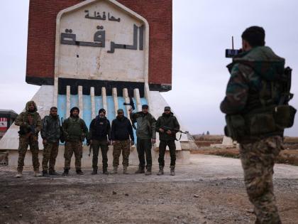 Syrian government soldiers pose for a photo taken by another soldier at the entrance to Raqqa.