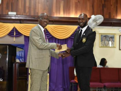 Customs Officer Earl Rayson (right) presents an undisclosed financial donation to Reverend Michael Hammond for the ministries of the First Church of the Open Bible. 