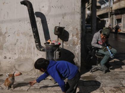 A boy plays with a cat on a street of the Kurdish-majority neighbourhood of Sheikh Maqsoud, in Aleppo, Syria.