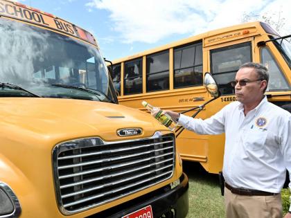 
Transport Minister Daryl Vaz pours rum on one of the buses procured for the rural school bus programme during a blessing ceremony at Jamaica House in St Andrew in August 2025.