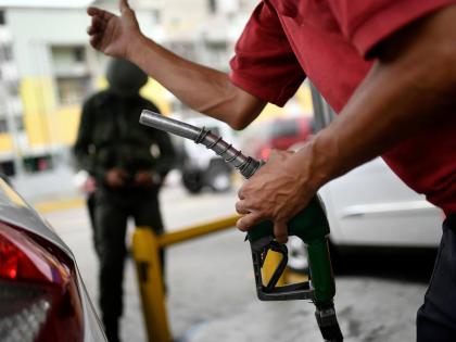 A worker holds a gas pump at a PDVSA state oil company gas station in Caracas, Venezuela, Monday, May 25, 2020. (AP Photo/Matias Delacroix, File)