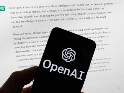 The OpenAI logo is displayed on a mobile phone in front of a computer screen with output from ChatGPT, March 21, 2023, in Boston. (AP Photo/Michael Dwyer, File)