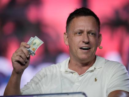 AP 
Peter Thiel, co-founder of PayPal and Palantir, offers a pair of hundred dollar bills to attendees during a keynote address at the Bitcoin Conference, April 7, 2022, in Miami Beach, Florida, USA. 