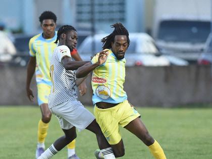 Jerome McLeary (centre) of Cavalier  challenges Waterhouse’s Omani Leacock during their Jamaica Premier League match at the Drewsland Mini Stadium yesterday. Home team Waterhouse won the game 2-1. 