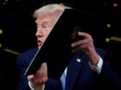 AP 
President Donald Trump holds up an executive order after signing it during the Commander-in-Chief’s Trophy presentation with the Navy Midshipmen football team in the East Room of the White House, Friday, March 20, 2026, in Washington. 