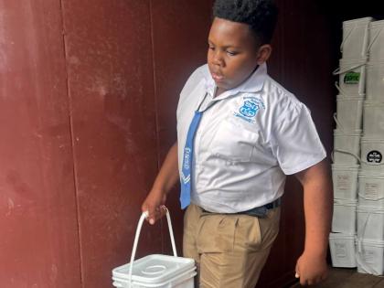 A student from Broughton Primary School helps to unload emergency food kits for Broughton during the distribution exercise in Westmoreland.