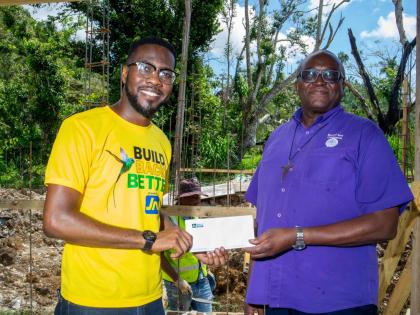 Omar Wright (left), lead, environment and community development at the JN Foundation presents a cheque to Reverend Father Garvin Augustine, executive director of Mustard Seed Communities to carry out repairs to Blessed Assurance in St James, which was dama