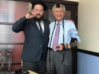 Hugh Hart (right) is seen wearing Tefillin alongside Rabbi Yaakov Raskin, who blows a ram’s horn in honor of the Jewish New Year.