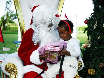 A child accepts a gift from Santa in this photo moment captured during an event at the William Knibb Memorial High School on Sunday, December 21, 2025. It was organised and hosted by FYI Consultancy Group in collaboration with the JN Foundation for residen