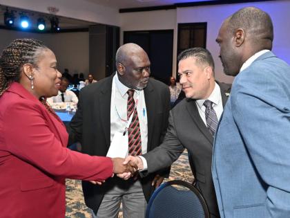 Rosemarie A. Henry (left), principal  officer and VP, risk and compliance, CUNA Caribbean Insurance Jamaica and president, Insurance Association of Jamaica (IAJ), greets Matthew Samuda second right), Minister of Water, Environment and Climate Change, as Ev