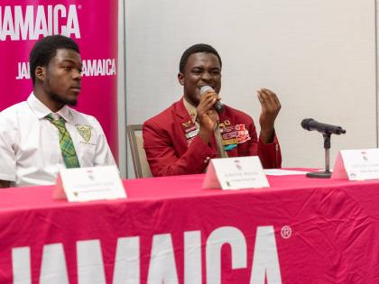 Nathan Clarke (right) of Glenmuir High delivers his presentation to top round one of the 2026 Junior Minister of Tourism Public Speaking Competition, held at AC Hotel Kingston on July 10. Looking on is Alwayne Wilson of Knockalva Technical High School.