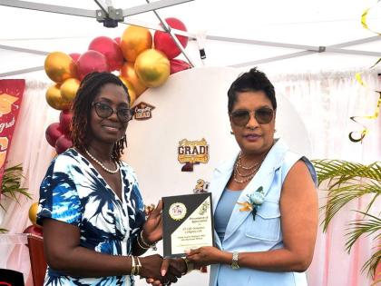 Janet Clarke (left), principal, Tidy Tots Educare in Black River, St Elizabeth, makes a presentation to Susan Holness (right), chief – new business and underwriting, JN Life Insurance, during the school’s recent graduation ceremony which was held at th
