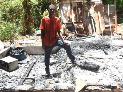 Robert Douglas stands amid the ruins of his home, which was destroyed in a suspected arson attack on Tuesday.