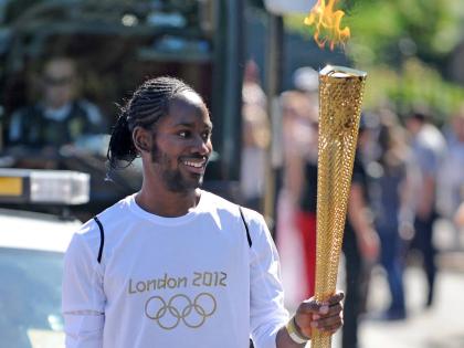 Torchbearer Jason Arday carries the Olympic Flame on the Torch Relay leg between Sutton and Merton, in London, July 23, 2012. 
