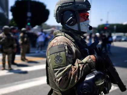 An ICE Special Response Team member stands guard outside the Metropolitan Detention Center, while protesters gather outside to denounce the US Immigration and Customs Enforcement, operations, in downtown Los Angeles. 