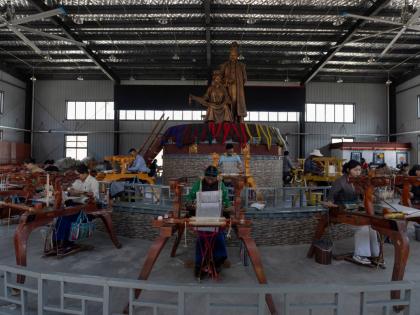 Workers weave Pulu, a traditional wooden fabric into clothing, at wooden looms near statues of Princess Wencheng and Tibetan King Songtsen Gampo at the Ethnic Huaji Handwoven Cooperative in Shannan in western China’s Tibet Autonomous Region.