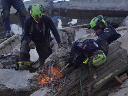 Rescue workers cut through debris as they search for survivors the day after an earthquake struck Cali, Colombia, Tuesday, Aug. 11, 2026. (AP Photo/Ivan Valencia)