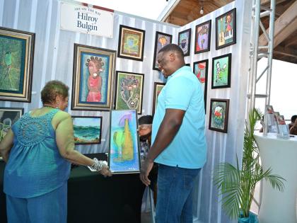 Artist and organiser Hilroy Bulgin completes a sale during the Art on the Bay exhibition at Pier 1 in Montego Bay.